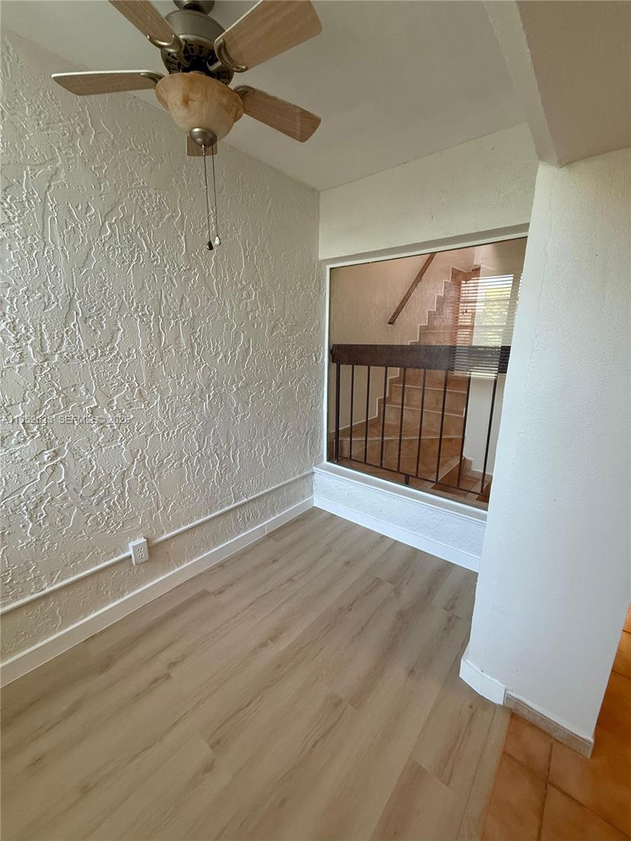 10641 Southwest 108th Avenue, Unit 3I Miami, FL 33176 - Photo 21 of 25 an empty room with wooden floor fan and windows