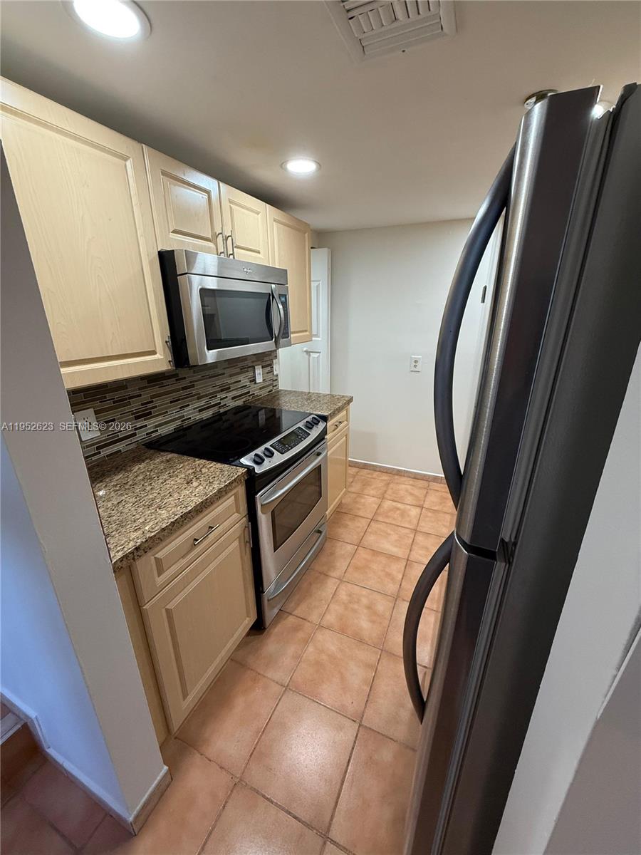 10641 Southwest 108th Avenue, Unit 3I Miami, FL 33176 - Photo 5 of 25 a kitchen with granite countertop a refrigerator stove and microwave