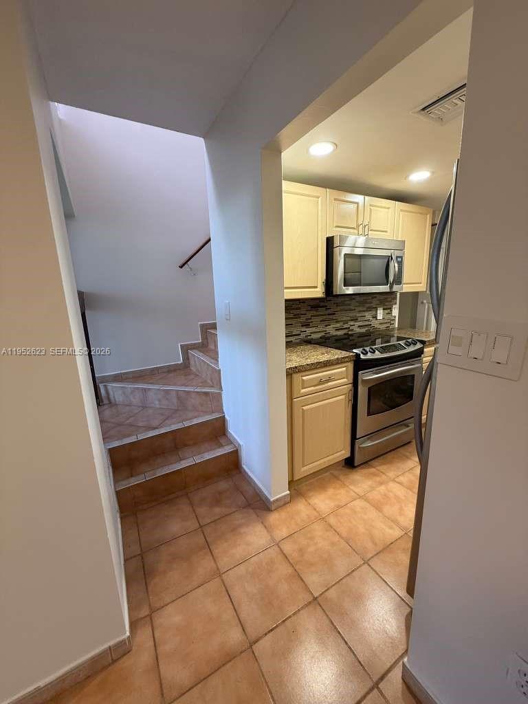 10641 Southwest 108th Avenue, Unit 3I Miami, FL 33176 - Photo 6 of 25 a kitchen with kitchen island granite countertop a stove top oven microwave and cabinets