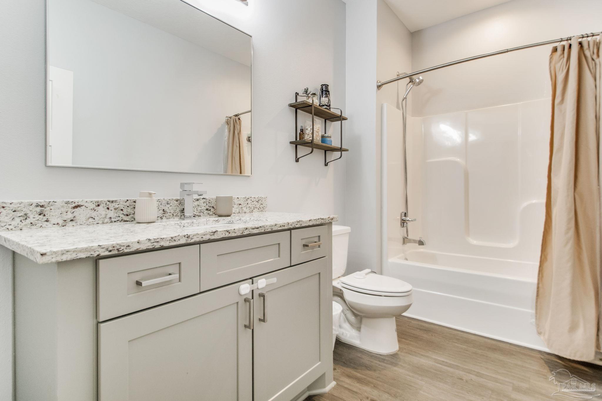 8245 Verano Street Navarre, FL 32566 - Photo 18 of 72 a bathroom with a granite countertop sink a toilet and a mirror