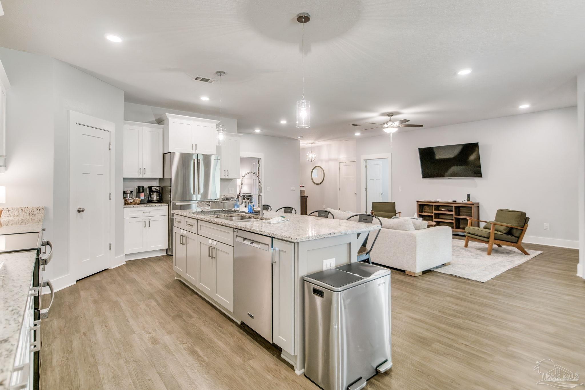 8245 Verano Street Navarre, FL 32566 - Photo 47 of 72 a large white kitchen with lots of counter space a sink a window and stainless steel appliances