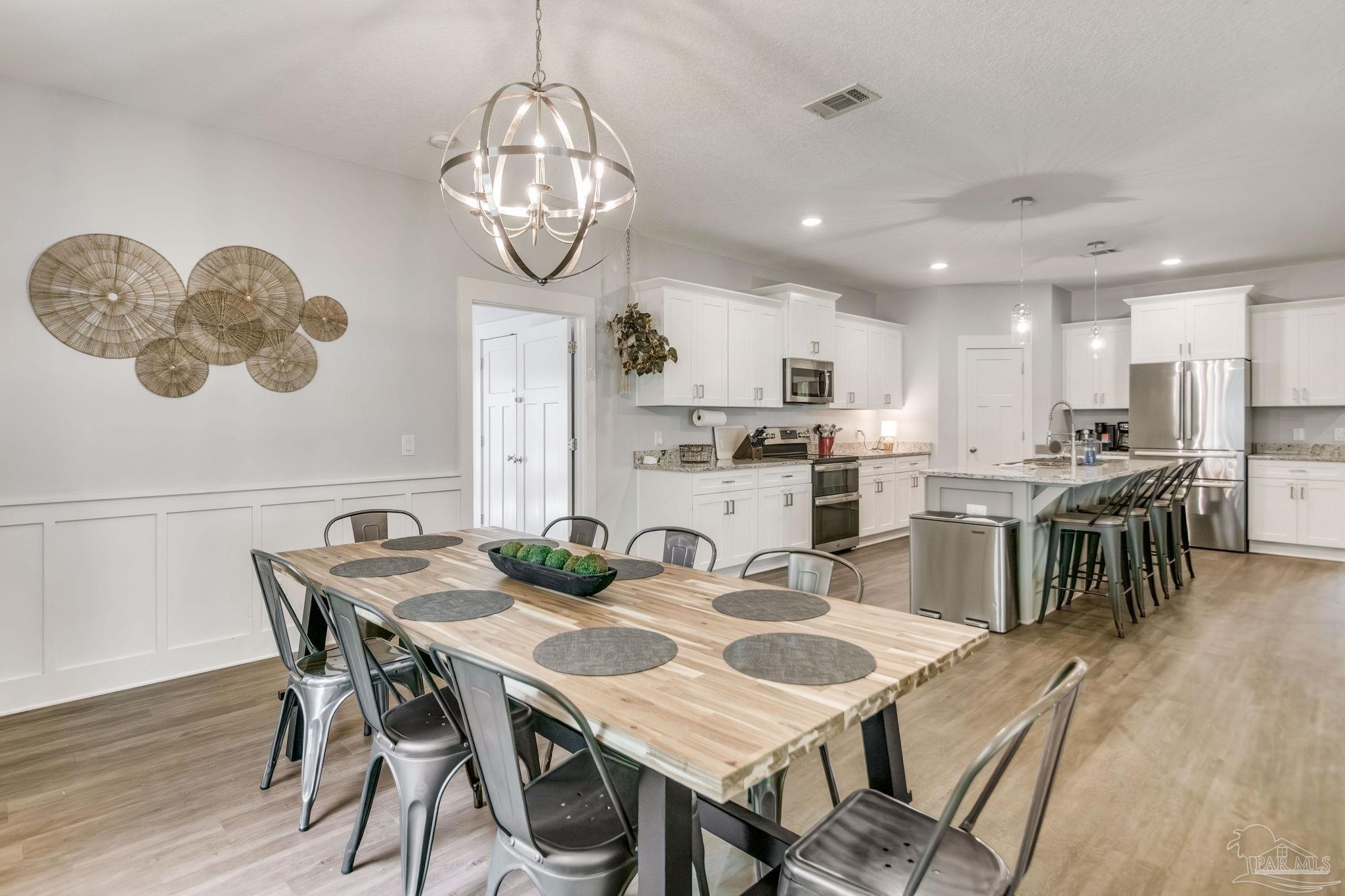8245 Verano Street Navarre, FL 32566 - Photo 58 of 72 a view of a dining room with furniture a chandelier and wooden floor