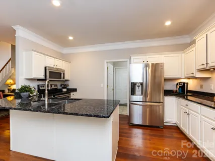 a kitchen with granite countertop a refrigerator and a stove top oven