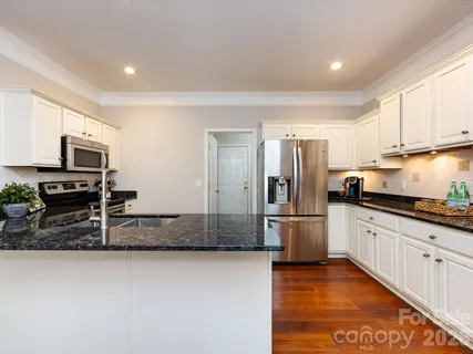 a kitchen with stainless steel appliances granite countertop a refrigerator a stove and a sink