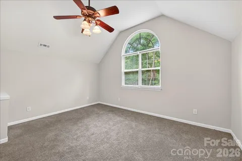an empty room with windows and fan