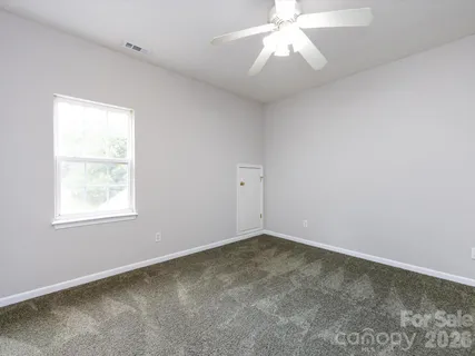 an empty room with a window and a fan