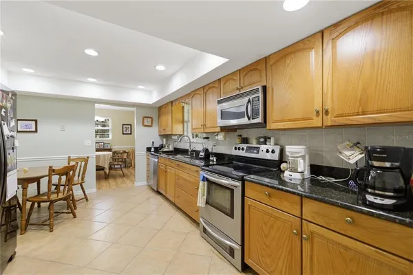 a kitchen with stainless steel appliances granite countertop a stove a sink a dining table and chairs