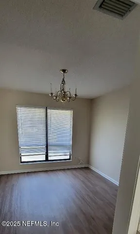 an empty room with wooden floor air conditioner and windows