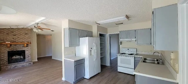 a kitchen with a refrigerator a stove top oven and wooden floor
