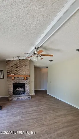 a view of an empty room with wooden floor and a fireplace
