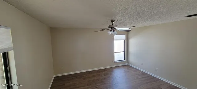 an empty room with a window and a chandelier fan