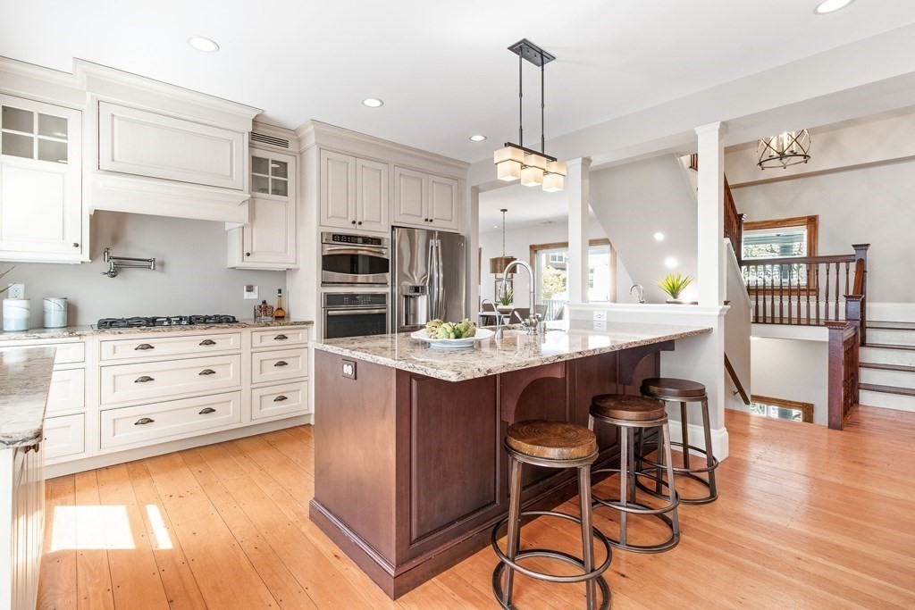 a kitchen with stainless steel appliances kitchen island granite countertop a wooden floor and white cabinets