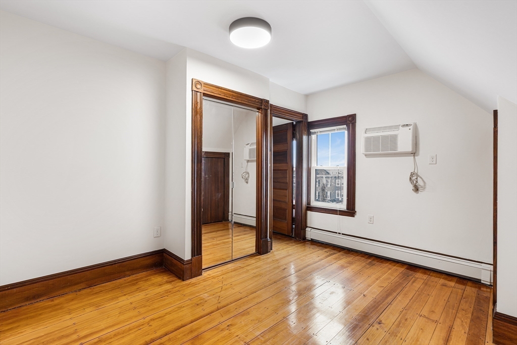 280 Broadway, Unit 5 Somerville, MA 02145 - Photo 9 of 13 a view of an empty room with window and wooden floor