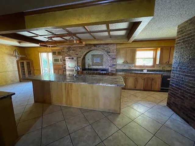 a large kitchen with stainless steel appliances granite countertop a stove a sink and a microwave