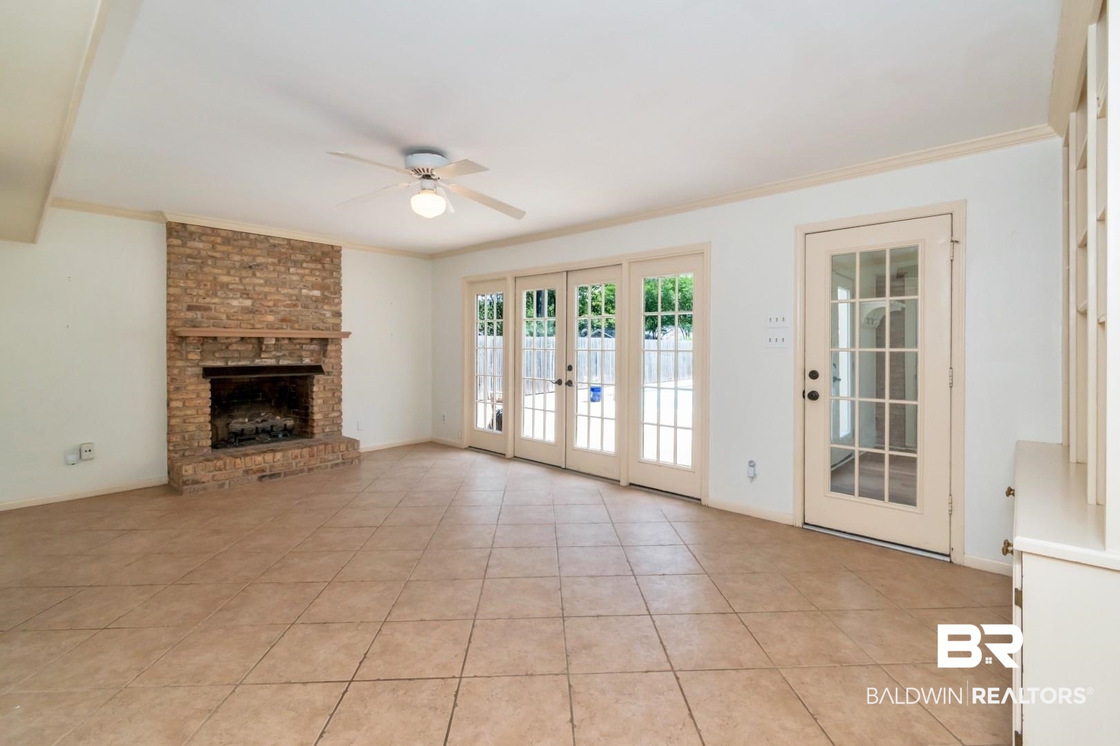 3755 Claridge Road North Mobile, AL 36608 - Photo 14 of 38 Unfurnished living room with a ceiling fan, french doors, crown molding, a brick fireplace, and light tile patterned flooring
