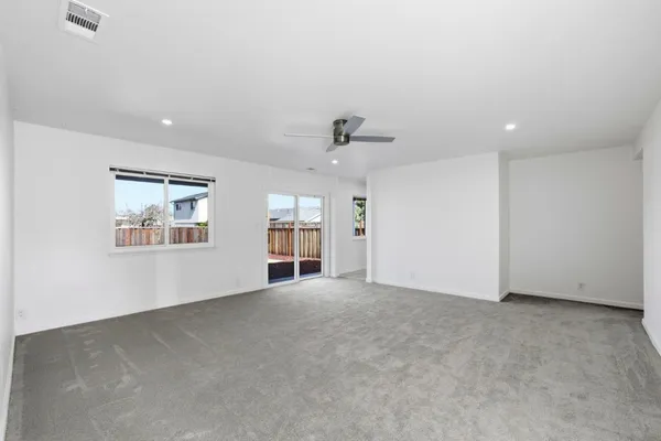 an empty room with windows and ceiling fan