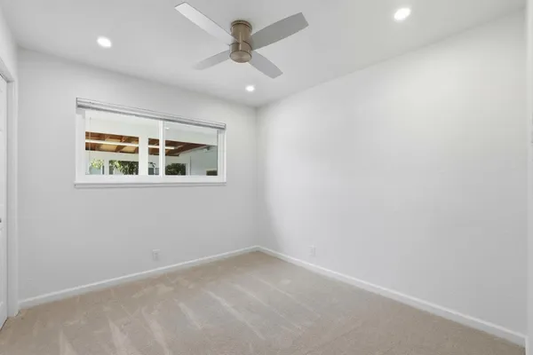 an empty room with a window and a ceiling fan