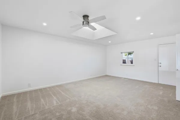 an empty room with ceiling fan and windows