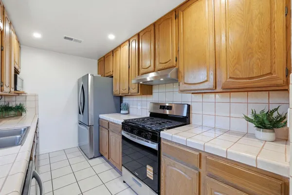 a kitchen with stainless steel appliances kitchen island granite countertop a refrigerator a stove a sink and cabinets