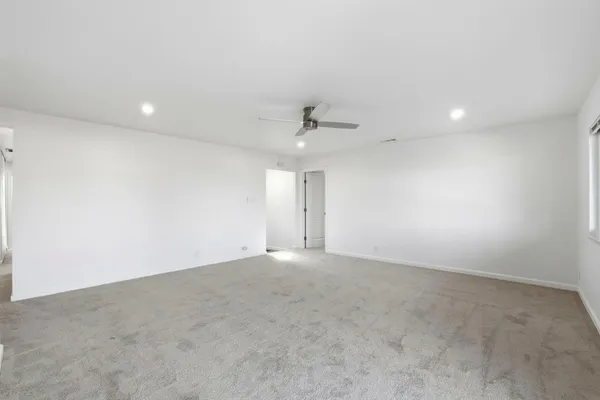 an empty room with a ceiling fan and carpet