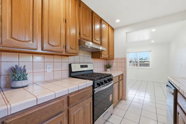 a kitchen with stainless steel appliances granite countertop a stove a sink and dishwasher with wooden cabinets