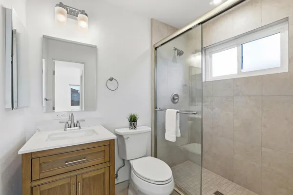 a bathroom with a sink a mirror a toilet and shower