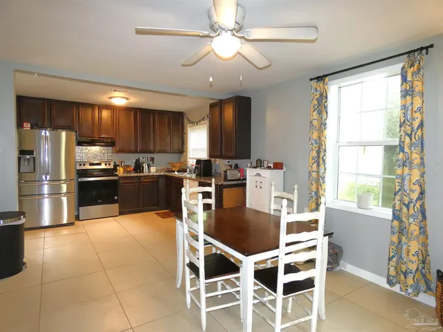 a kitchen with granite countertop stainless steel appliances a sink a stove a refrigerator cabinets and a dining table