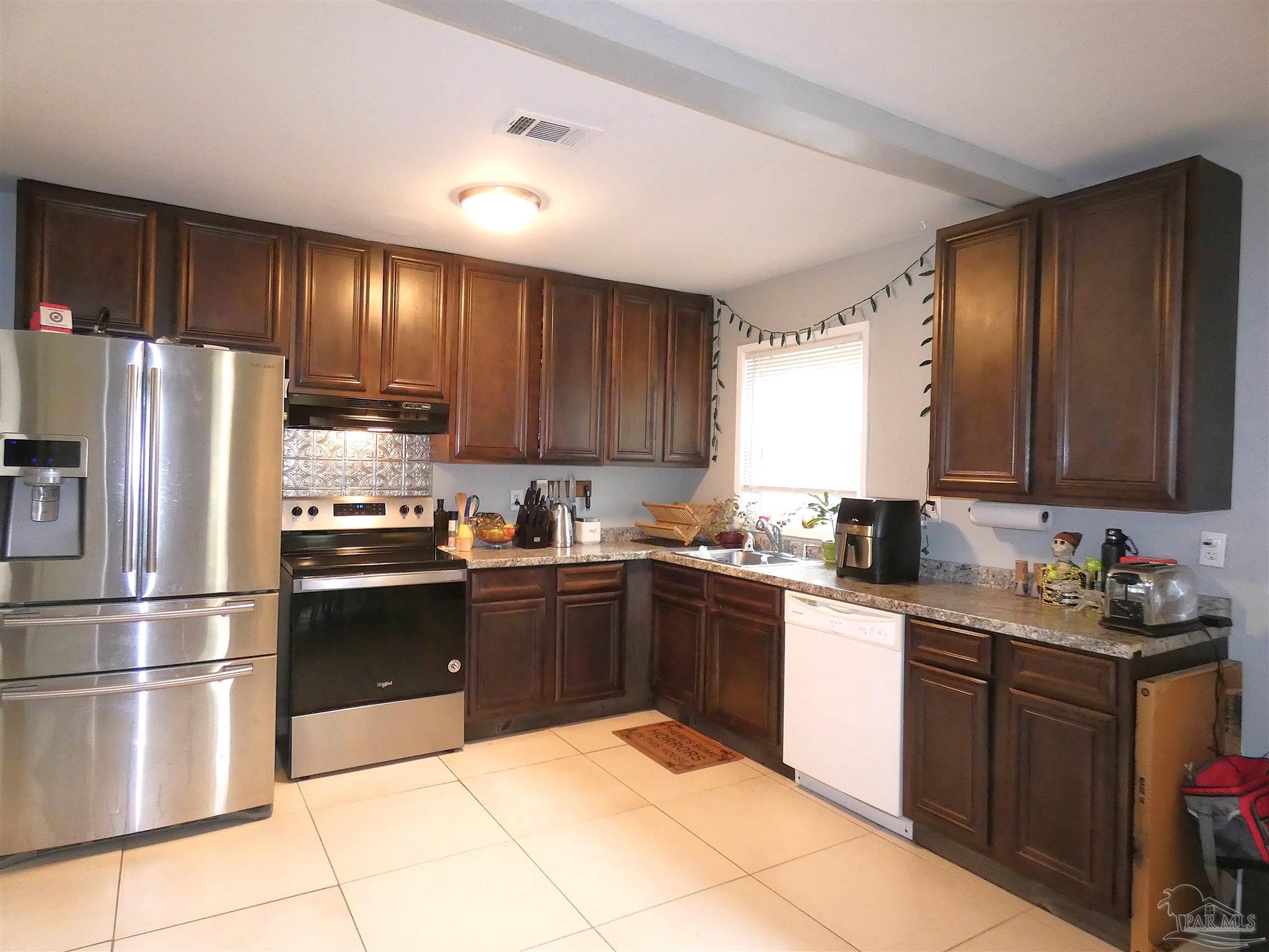 7704 West Gadsden Street Pensacola, FL 32506 - Photo 6 of 18 a kitchen with granite countertop a refrigerator stove top oven and sink