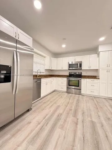 a kitchen with stainless steel appliances granite countertop a refrigerator and a stove top oven