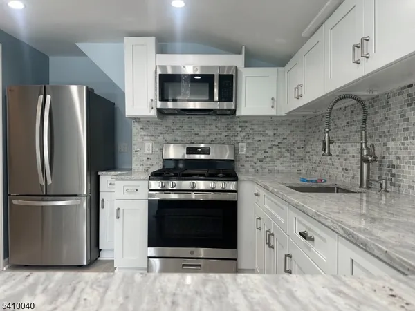 a kitchen with stainless steel appliances granite countertop a stove a refrigerator and a microwave