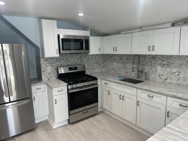a kitchen with cabinets stainless steel appliances and wooden floor
