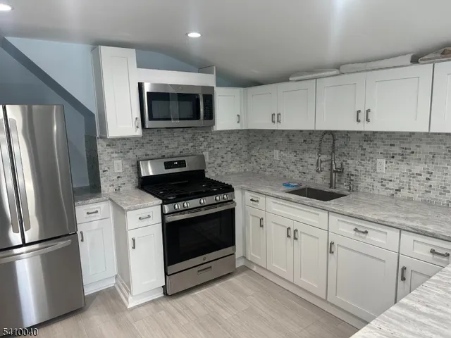 a kitchen with cabinets stainless steel appliances and wooden floor
