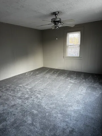 an empty room with a chandelier fan and windows