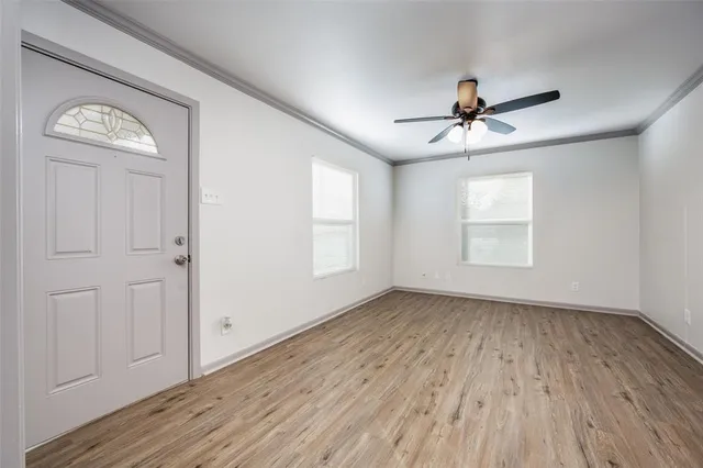 a view of empty room with wooden floor and fan