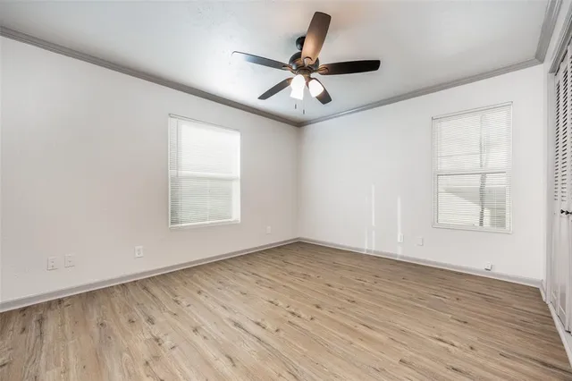 an empty room with wooden floor ceiling fan and windows