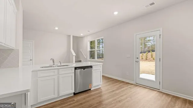 a kitchen with stainless steel appliances granite countertop a sink cabinets and wooden floor