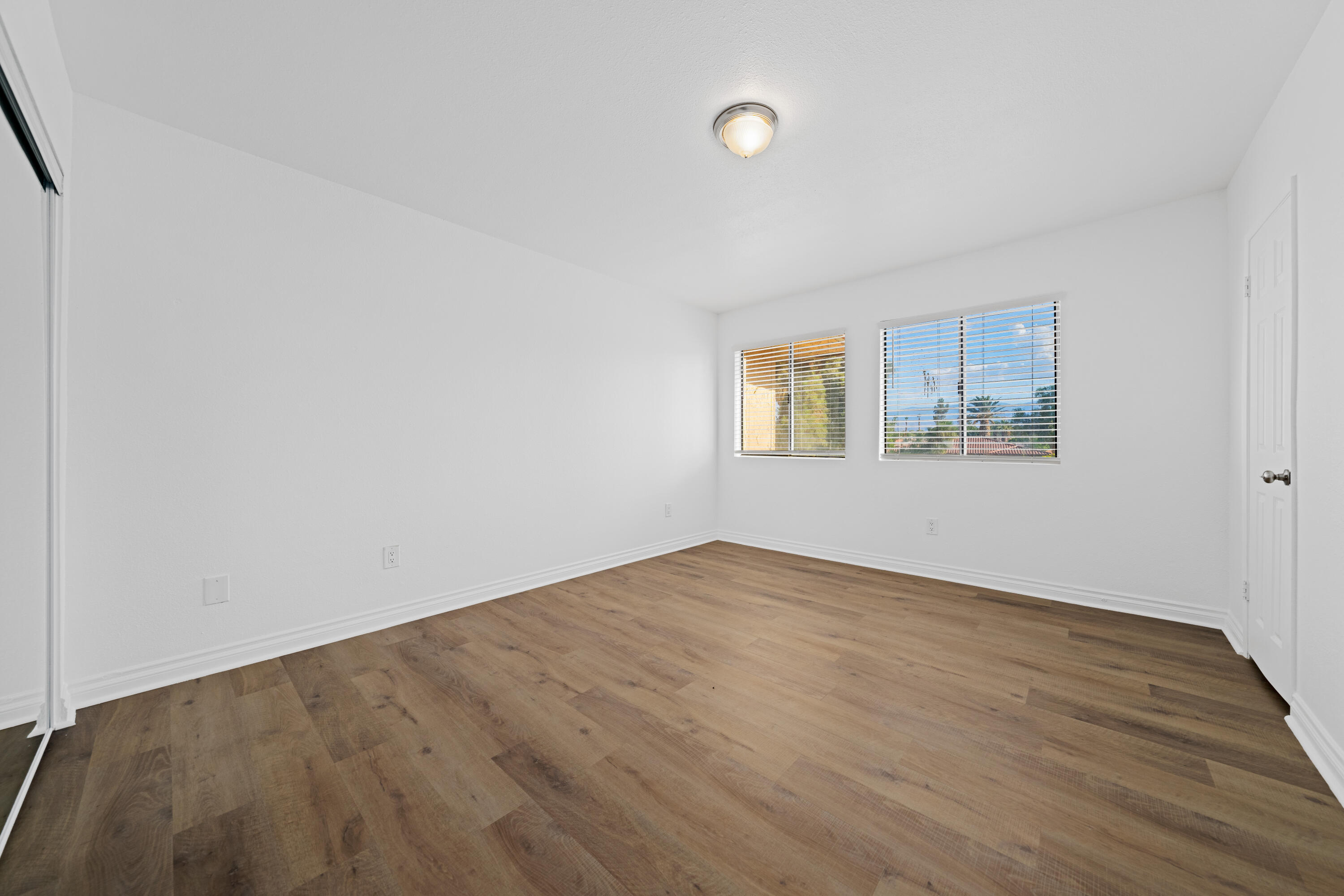 82567 Ave 48, Unit 12 Indio, CA 92201 - Photo 9 of 23 an empty room with wooden floor and windows