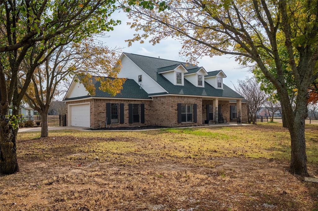 364 Parker Road, Unit A Van Alstyne, TX 75495 - Photo 24 of 39 Brick exterior with white trim, green shingle roof, and a covered front porch featuring three dormer windows