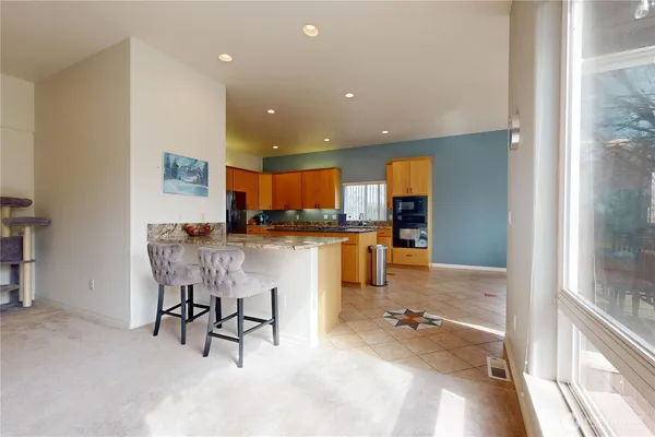 a dining hall with stainless steel appliances kitchen island granite countertop a refrigerator and a sink