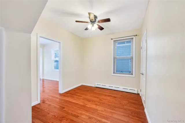 an empty room with wooden floor and ceiling fan