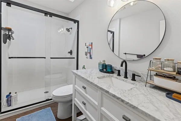 a bathroom with a granite countertop sink mirror vanity and toilet