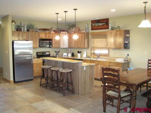 a kitchen with kitchen island a dining table chairs sink and cabinets