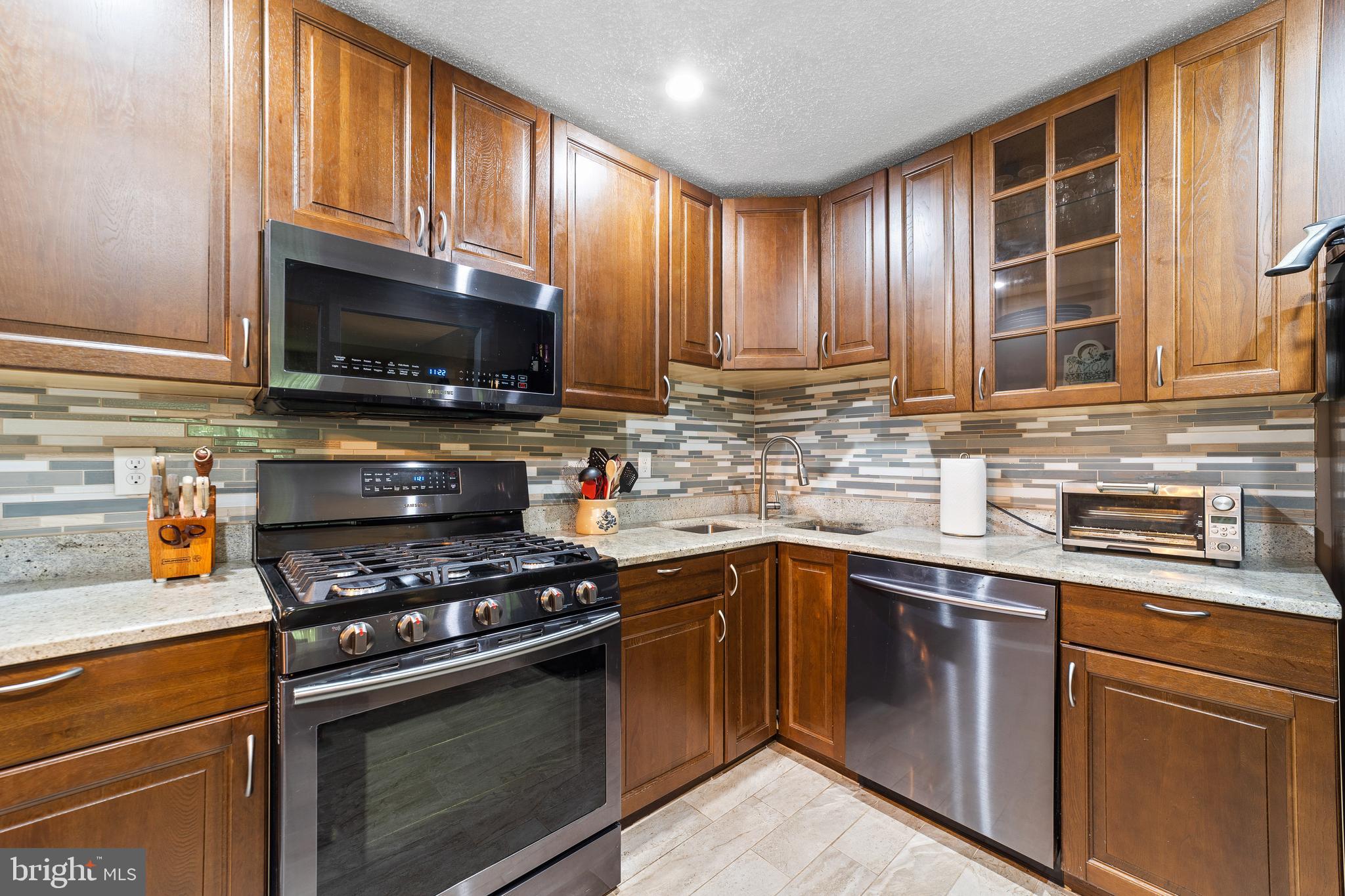 a kitchen with granite countertop wooden cabinets stainless steel appliances and a window