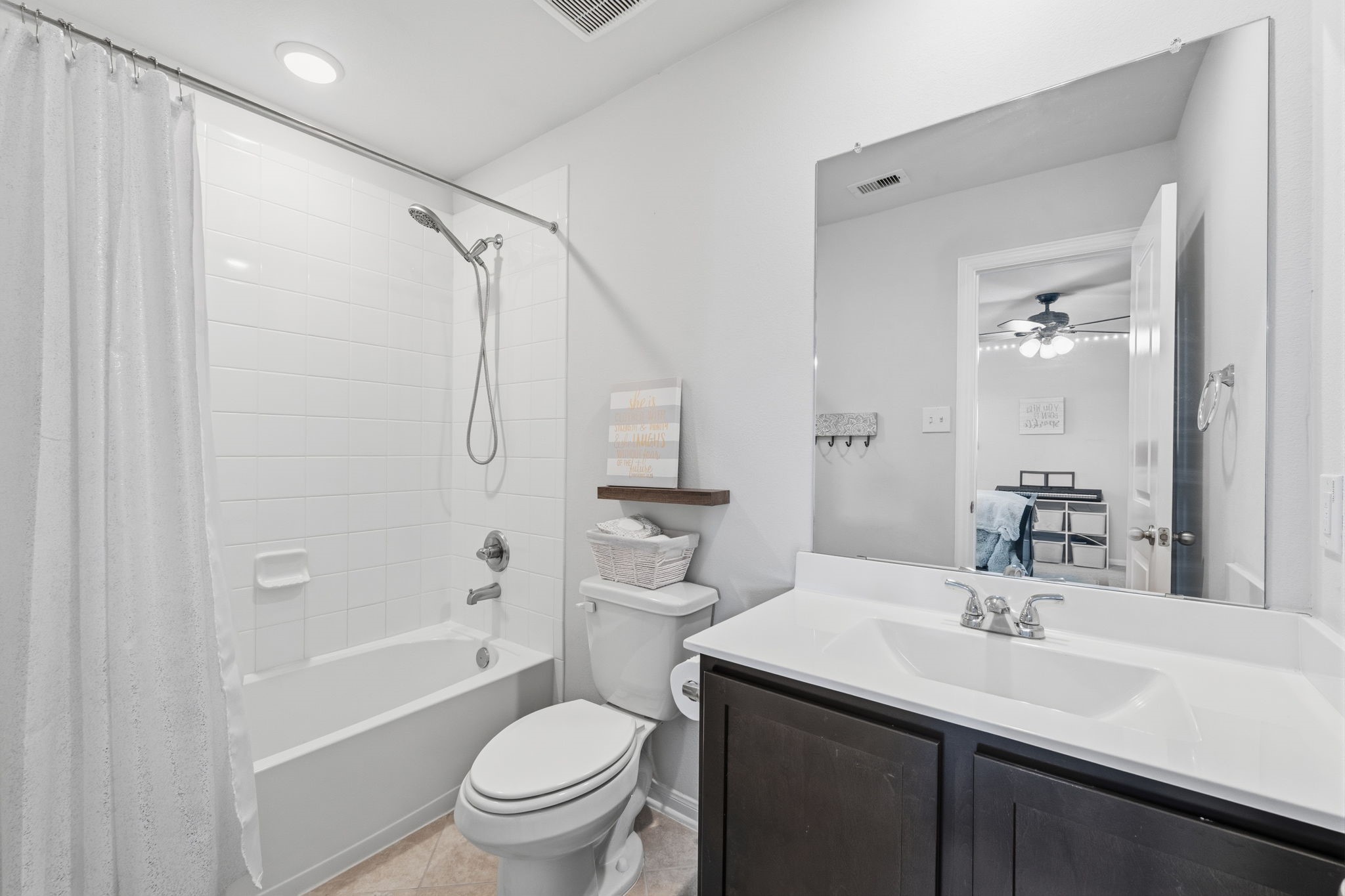 2401 Abbot Brk Drive Rosharon, TX 77583 - Photo 30 of 50 The private secondary bath for Bedroom 2 is thoughtfully designed with stylish tile flooring laid on the diagonal, adding a refined designer touch. Features include a vanity with a sleek solid-surface countertop and integrated rectangular sink, along with a tiled shower/tub combination enhanced by a detachable handheld shower head for added comfort and convenience.