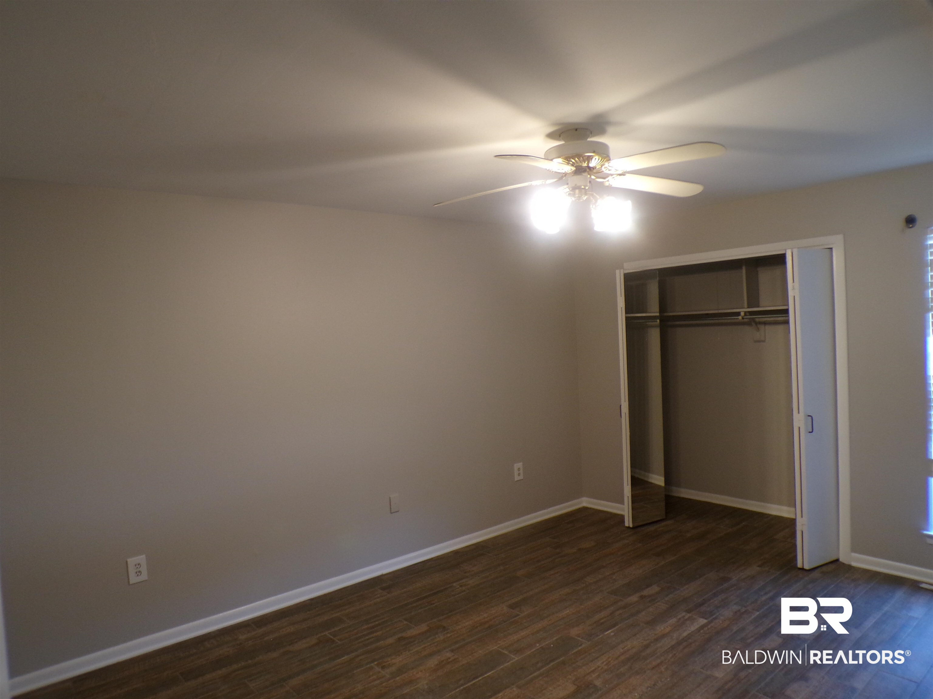 1152 North Alston Street, Unit 1152 Foley, AL 36535 - Photo 11 of 16 Room featuring wood-finish flooring, neutral wall tones, and a ceiling fan with integrated lighting