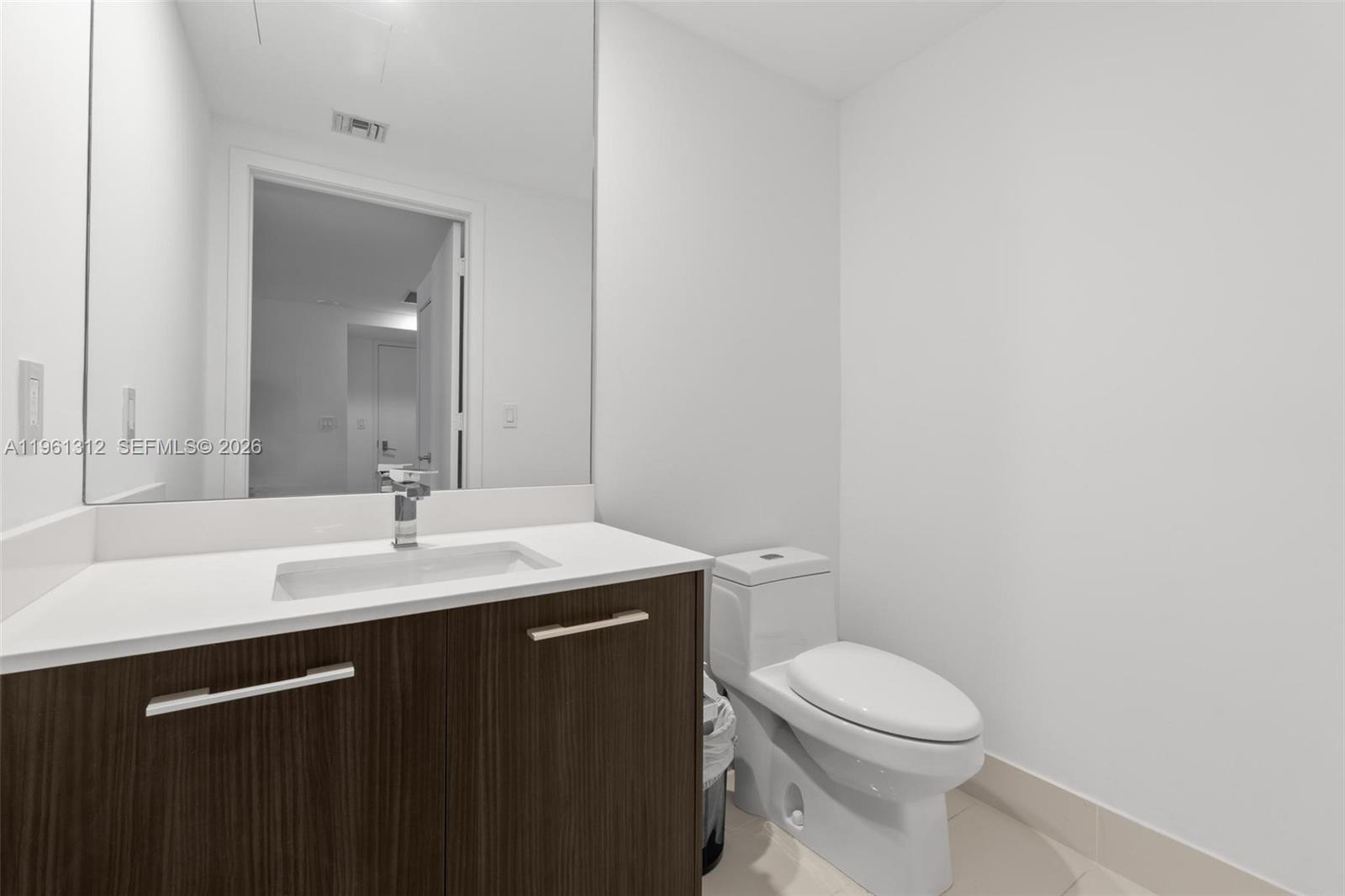 45 Southwest 9th Street, Unit 1109 Miami, FL 33130 - Photo 12 of 25 a bathroom with a granite countertop toilet a sink and a mirror