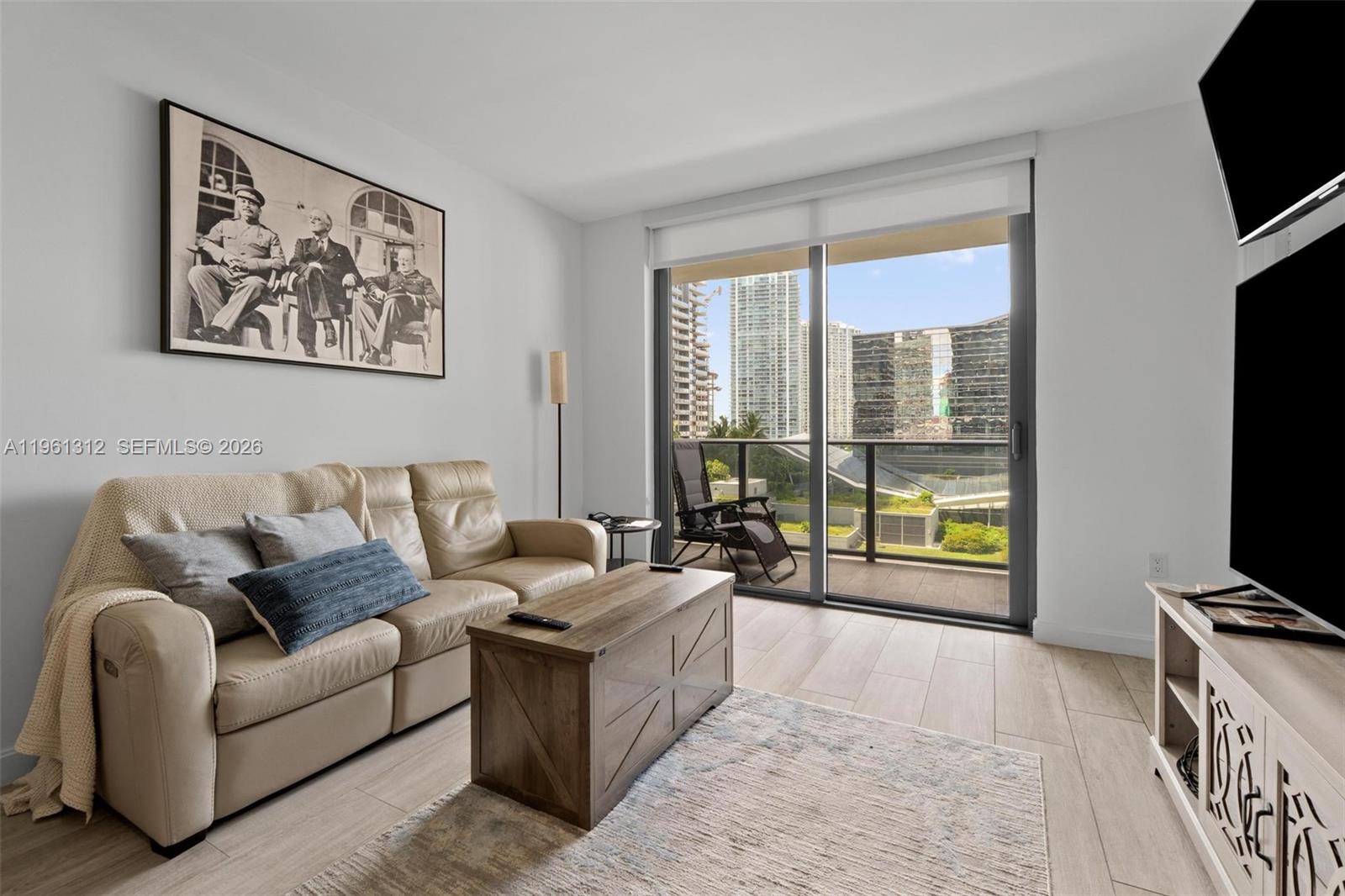 45 Southwest 9th Street, Unit 1109 Miami, FL 33130 - Photo 5 of 25 a living room with furniture a flat screen tv and a floor to ceiling window