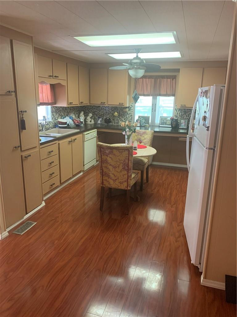 8257 East Club Road Boca Raton, FL 33433 - Photo 14 of 28 a kitchen with stainless steel appliances granite countertop a refrigerator a sink dishwasher a stove a dining table and chairs with wooden floor