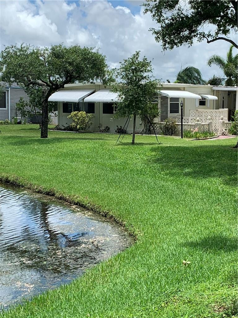 8257 East Club Road Boca Raton, FL 33433 - Photo 2 of 28 a front view of a house with a yard and green space