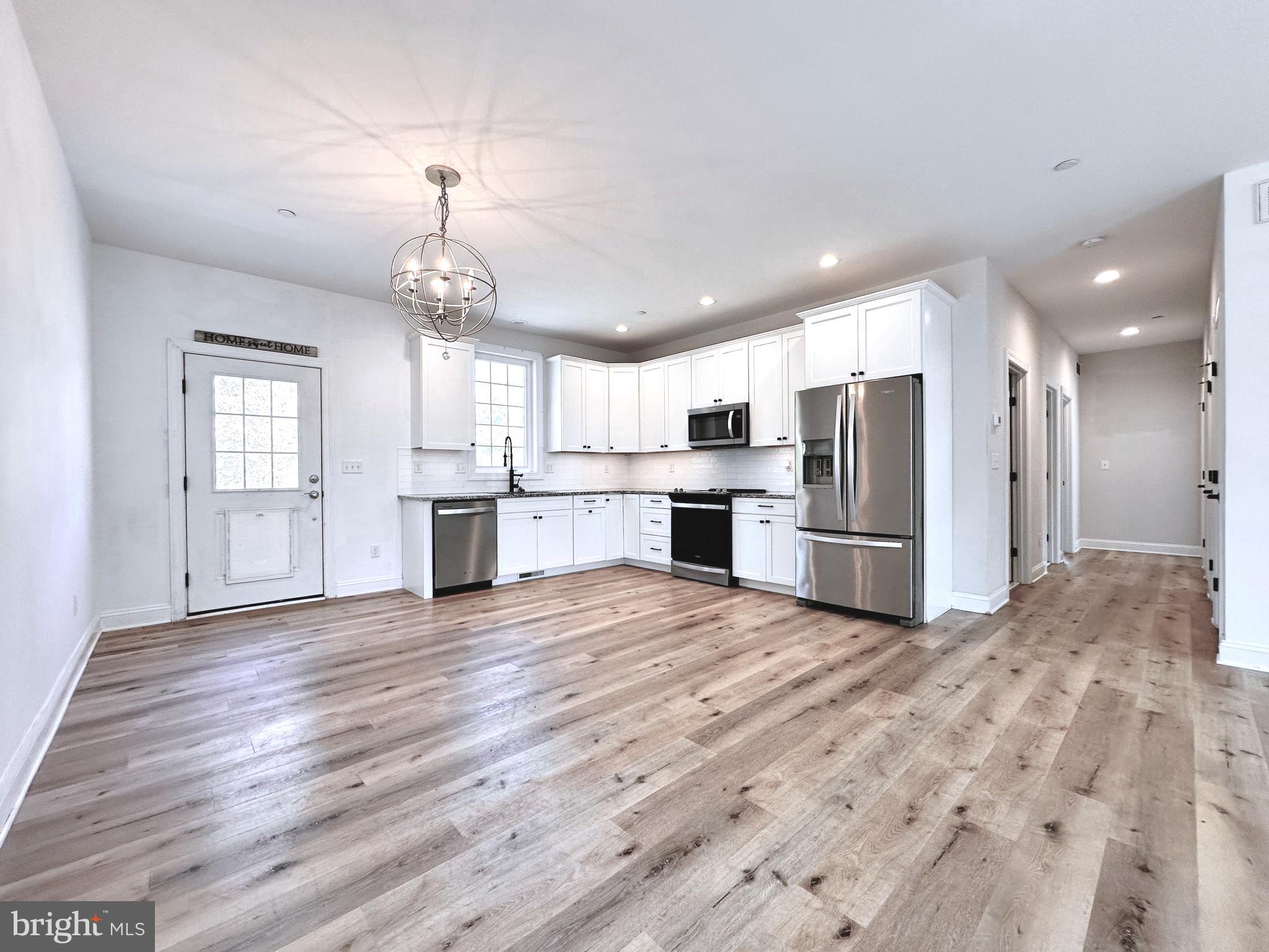 102 Pine Street Crumpton, MD 21628 - Photo 7 of 31 a view of kitchen with refrigerator microwave and wooden floor